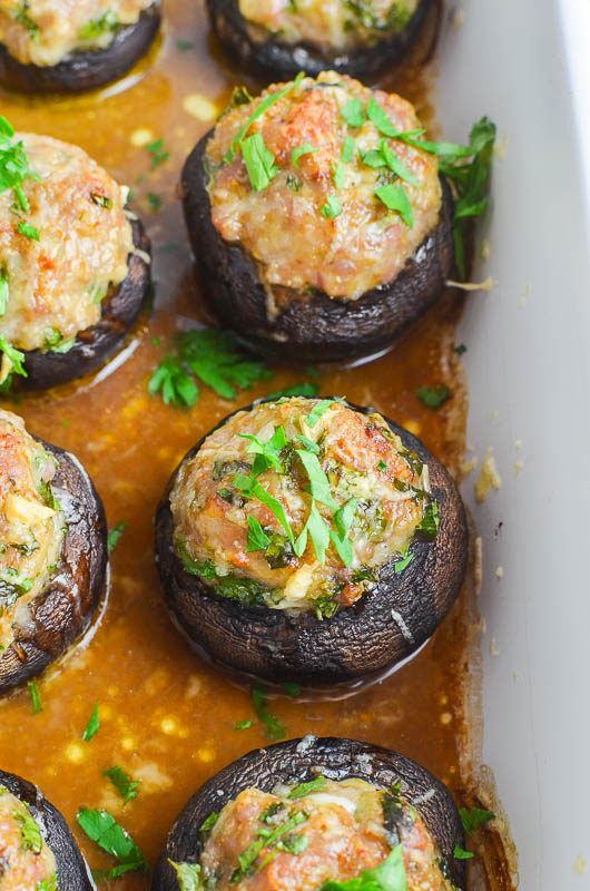 Sausage stuffed mushrooms in a white casserole dish. 