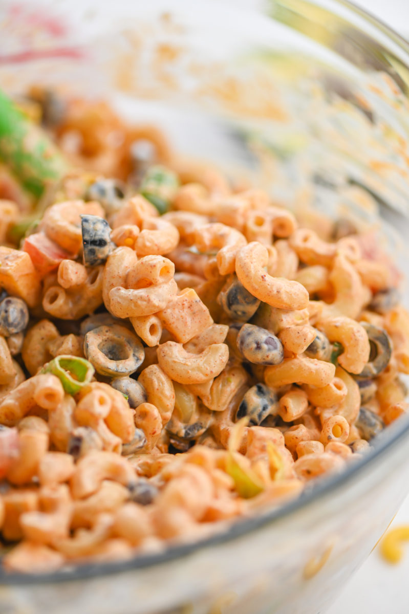 Close up of seven layer dip pasta salad in a glass bowl.