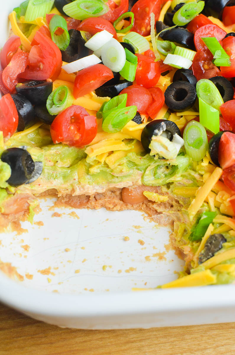 Showing the layers of seven layer dip in a white dish