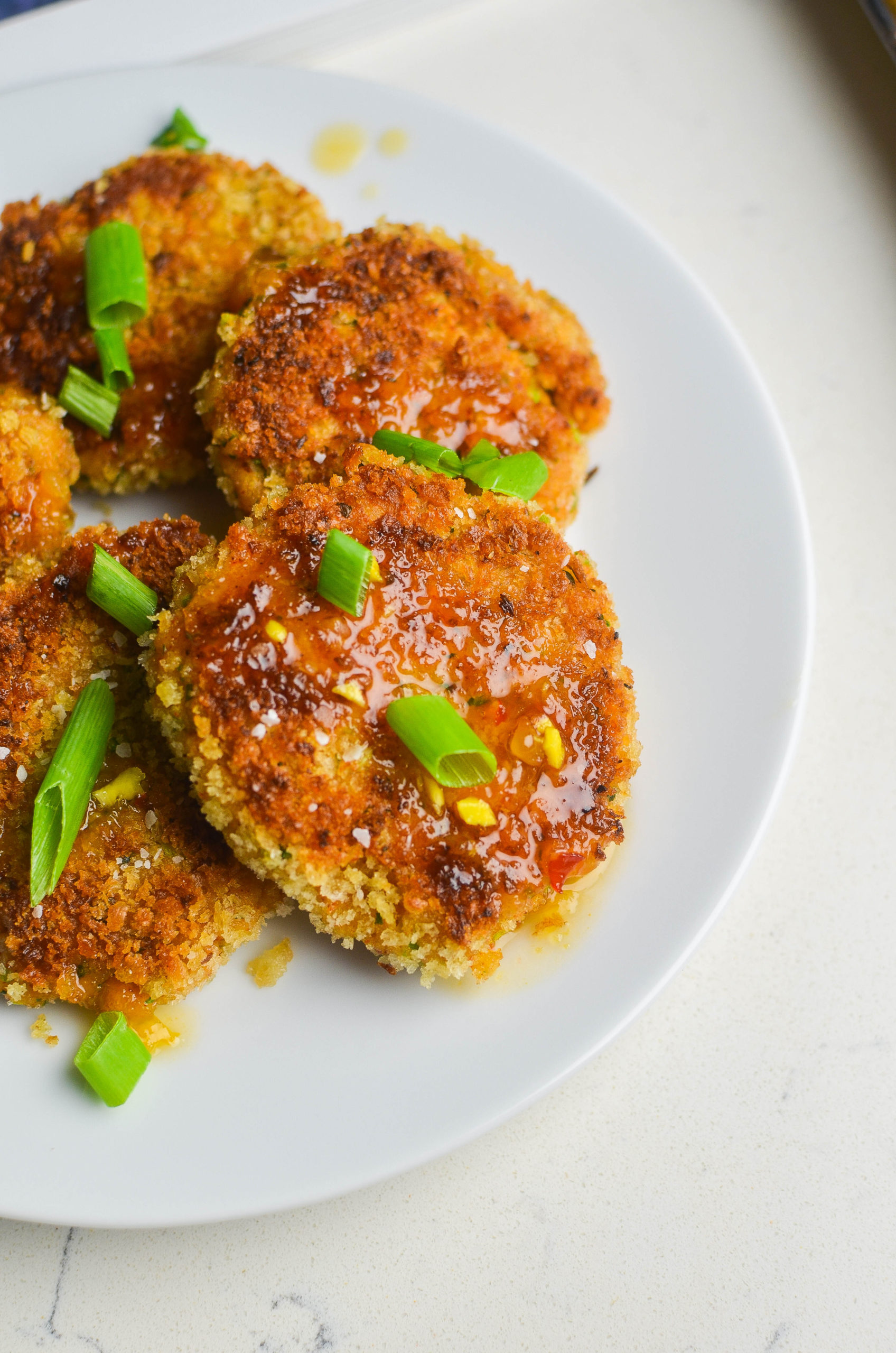 Side angle photo of shrimp cakes on white plate. 