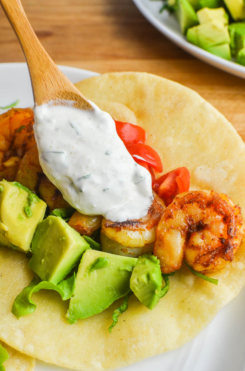 Drizziling cilantro lime sour cream on shrimp tacos. 