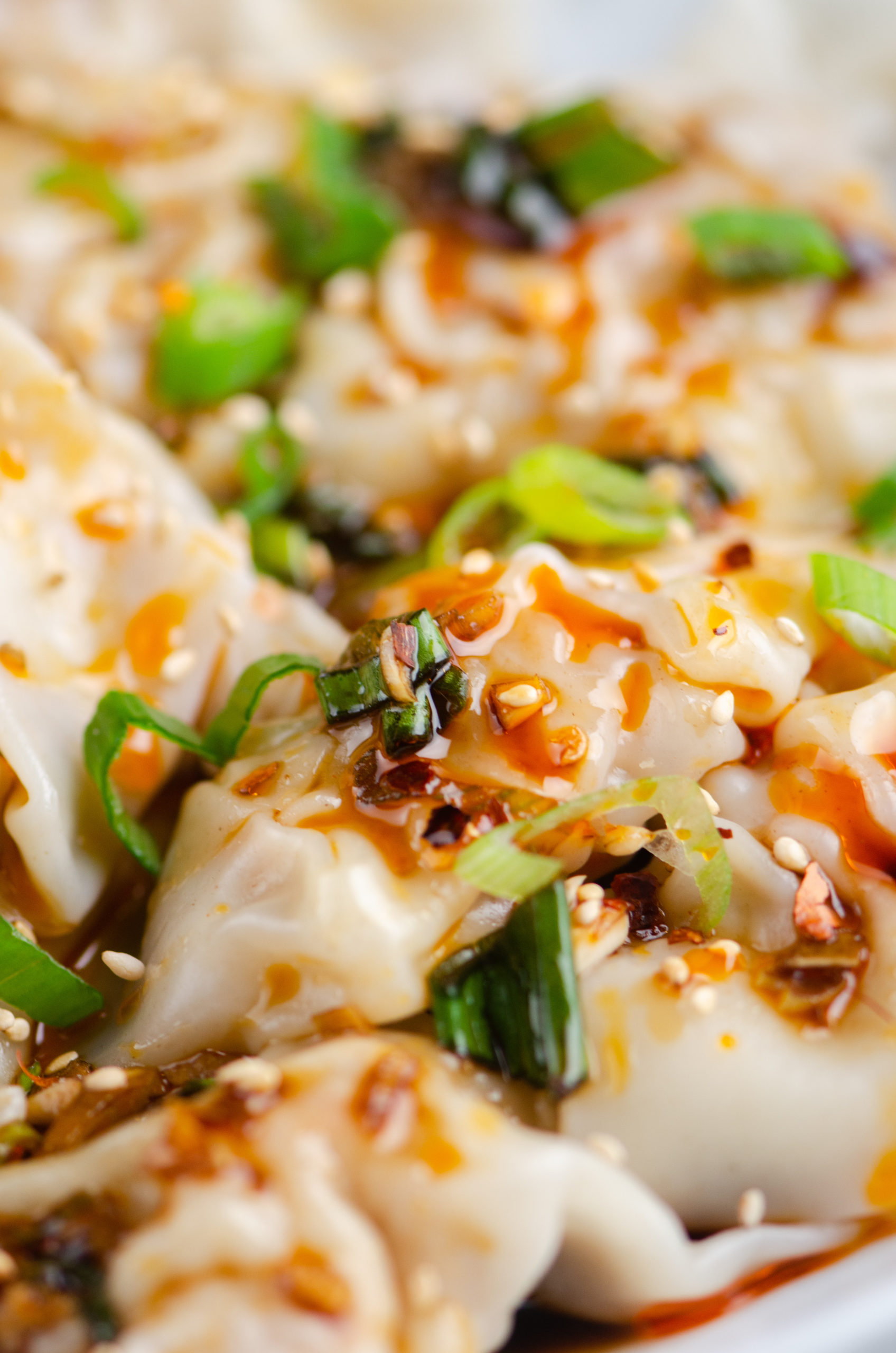 Close up photo of wontons with spicy sauce over the top. 