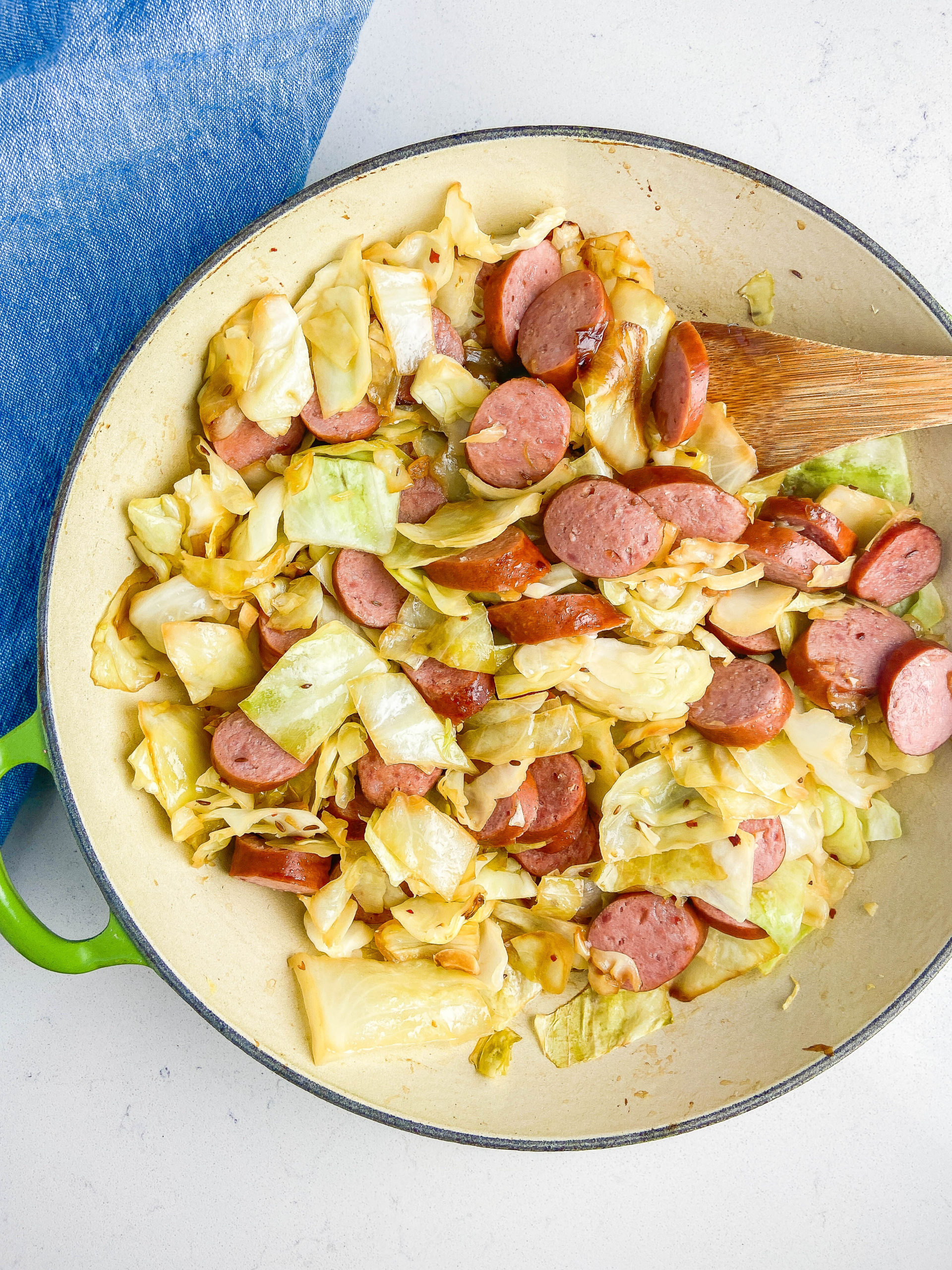 Overhead photo of cabbage and kielbasa in a skillet. 