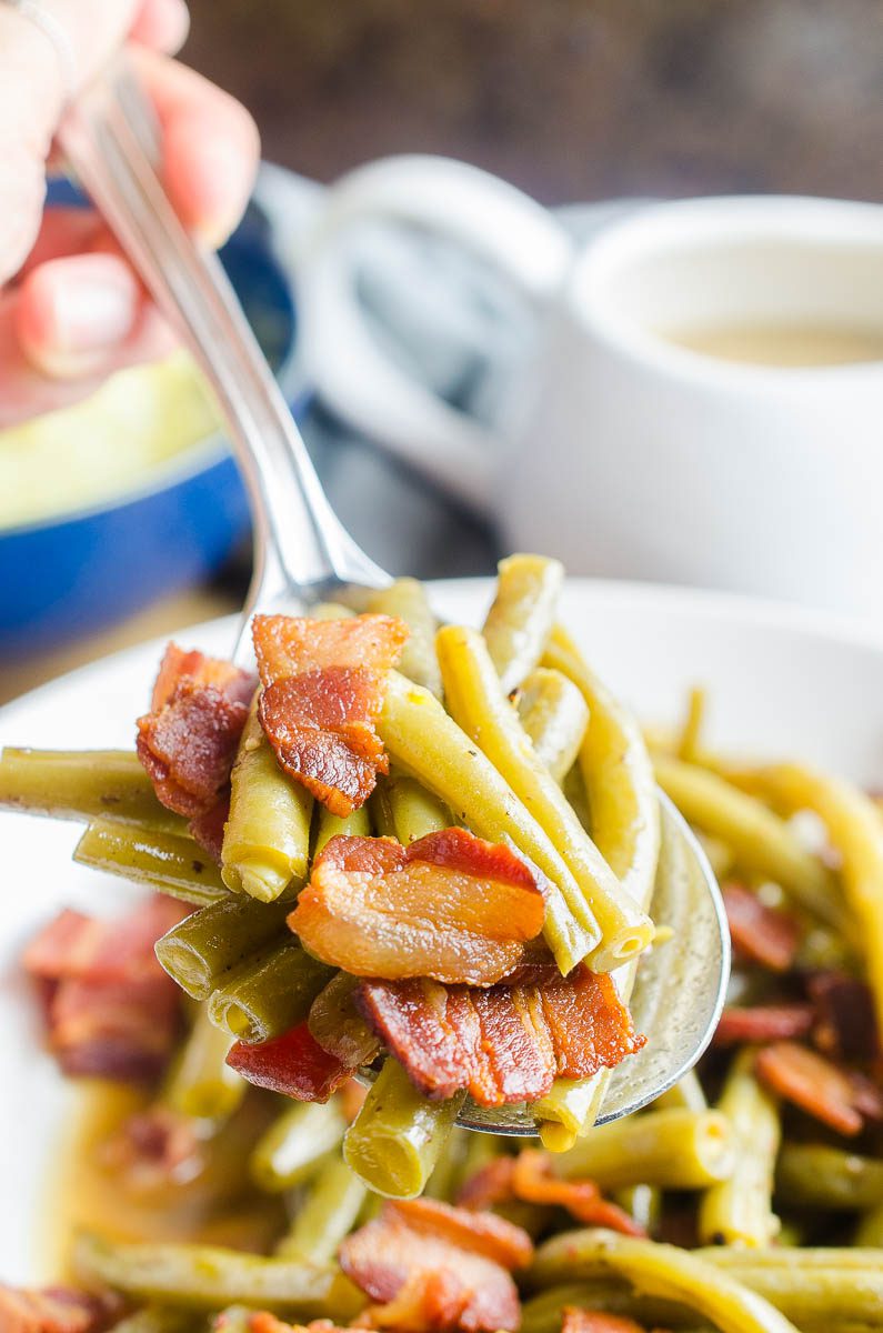 A spoonful of green beans with bacon. 
