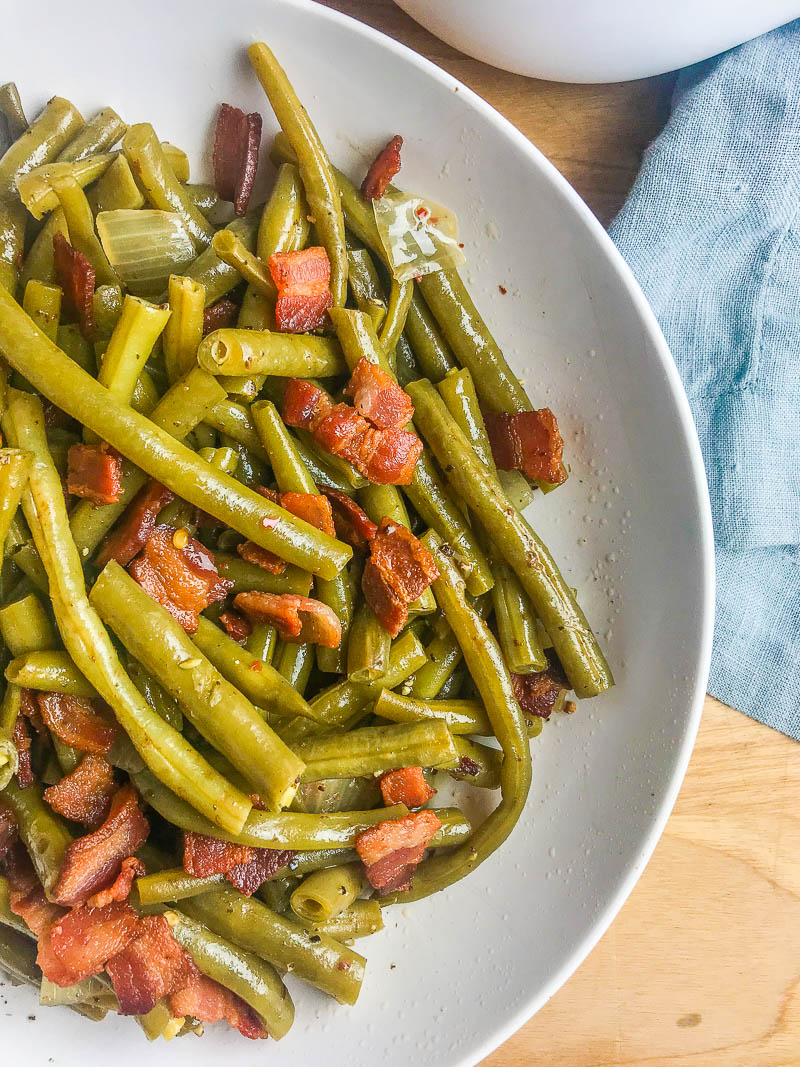 Southern Style Green Beans with Bacon is a comfort food classic. Fresh green beans slow simmered with onions, chicken broth and bacon. Perfect for holidays and Sunday supper! 