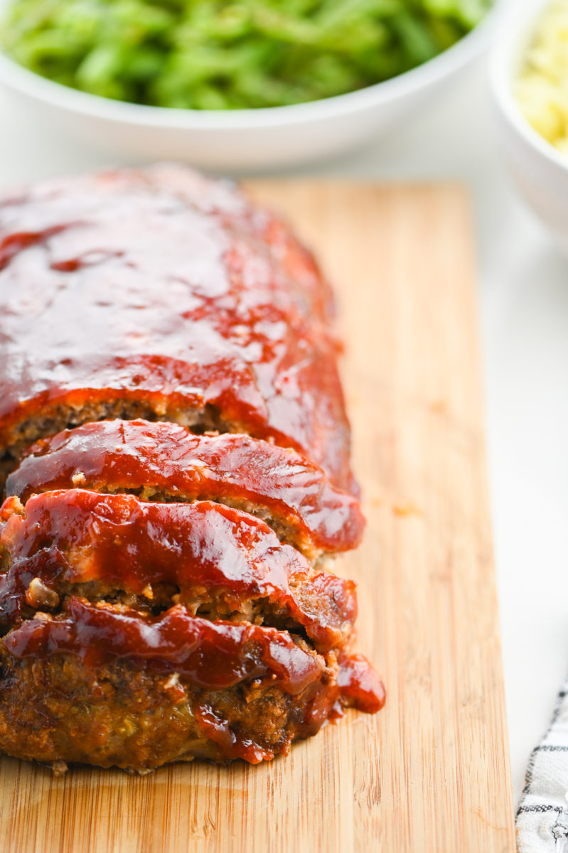 Sliced sriracha meatloaf on a wooden cutting board. 