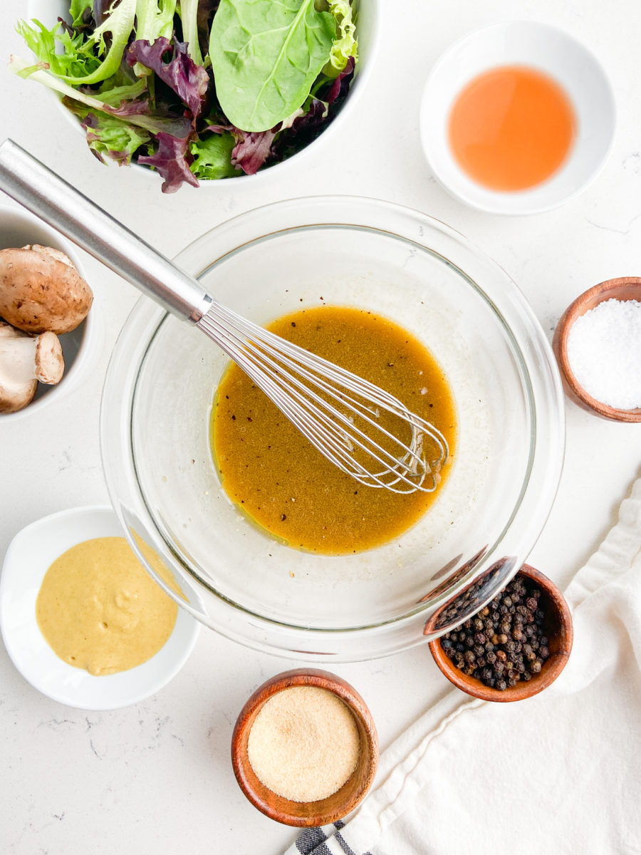 Steak salad dressing in glass bowl with whisk. 