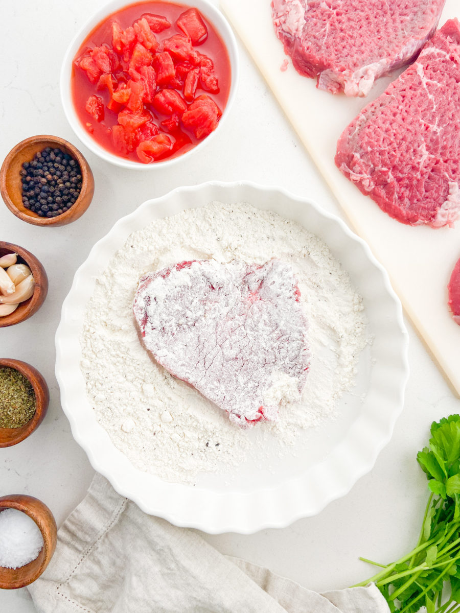 Dredging round steak in flour.