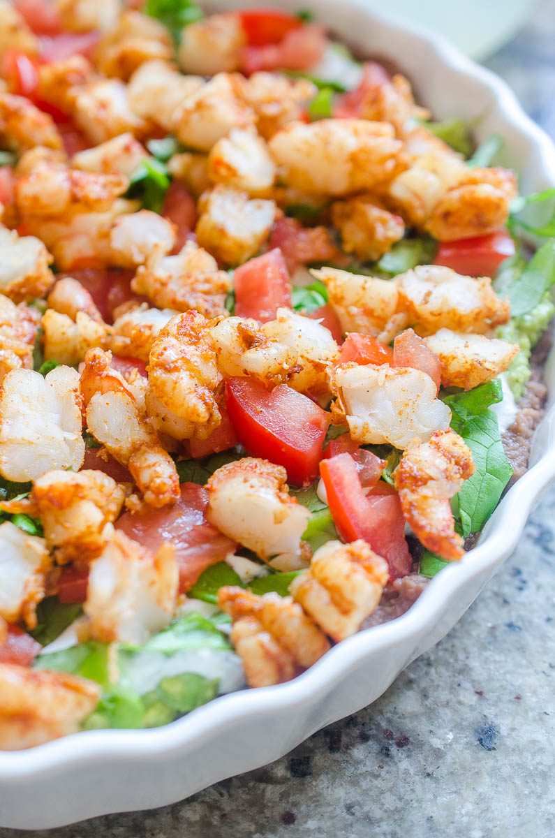 Everyone one loves a good shrimp taco. Everyone loves a good taco dip. I've put them together in this Taco Shrimp Dip with black beans, lettuce, cilantro sour cream, tomatoes and spicy shrimp.