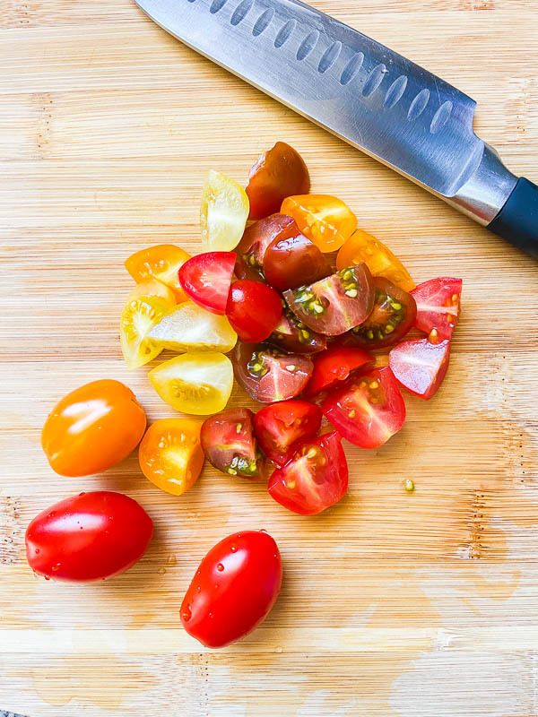 Chopped tomatoes on a wooden cutting board with a knife. 