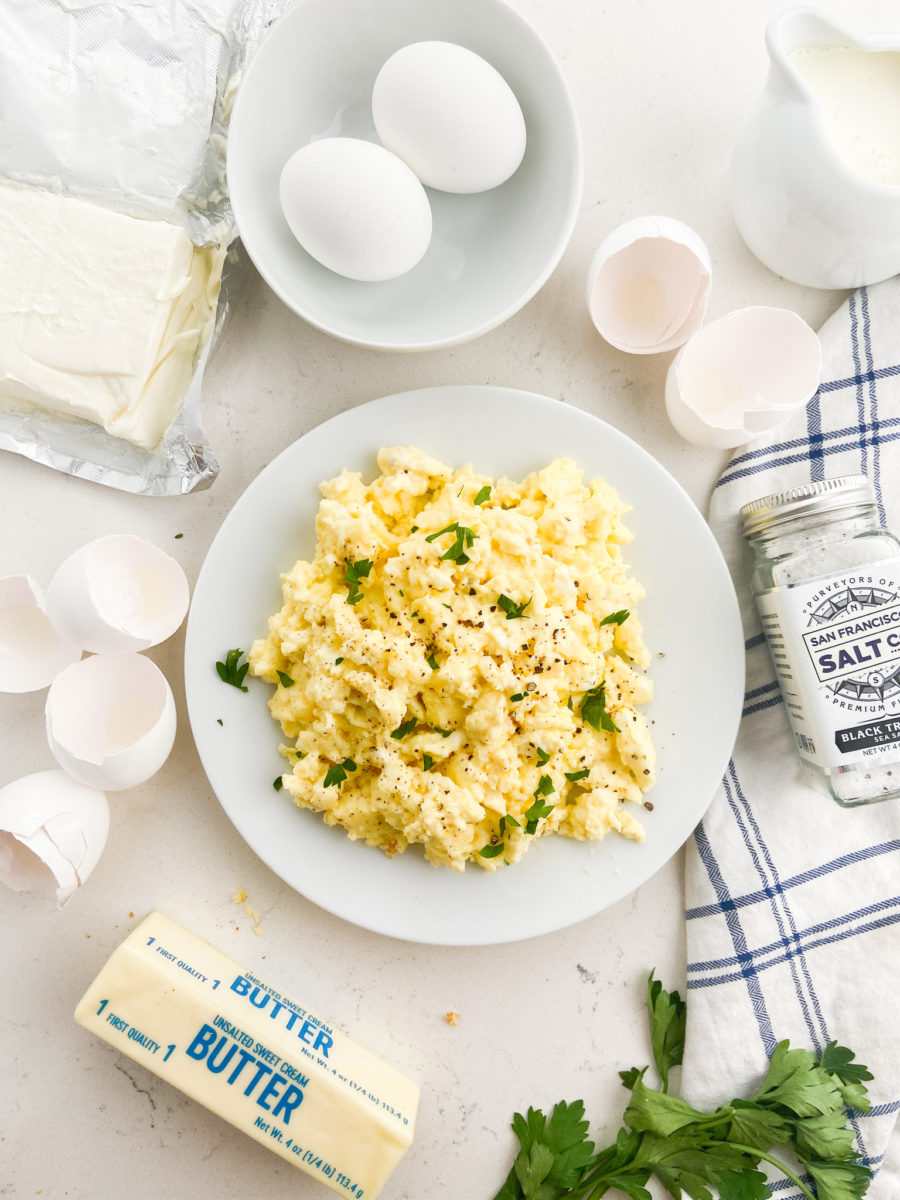 Truffle scrambled eggs on white plate with butter, eggshells and napkin. 