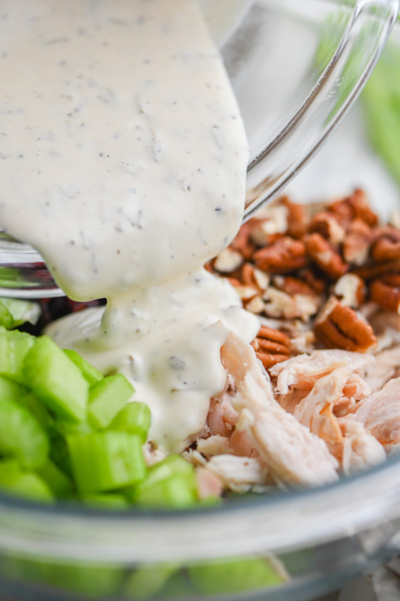 Pouring dressing over turkey salad. 