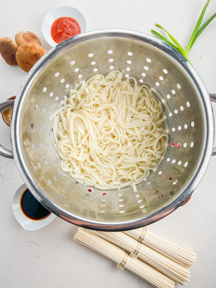Udon noodles in a strainer.