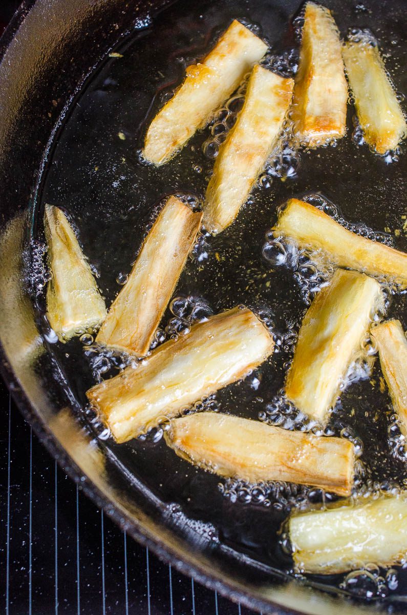 Frying yuca fries in a cast iron skillet 